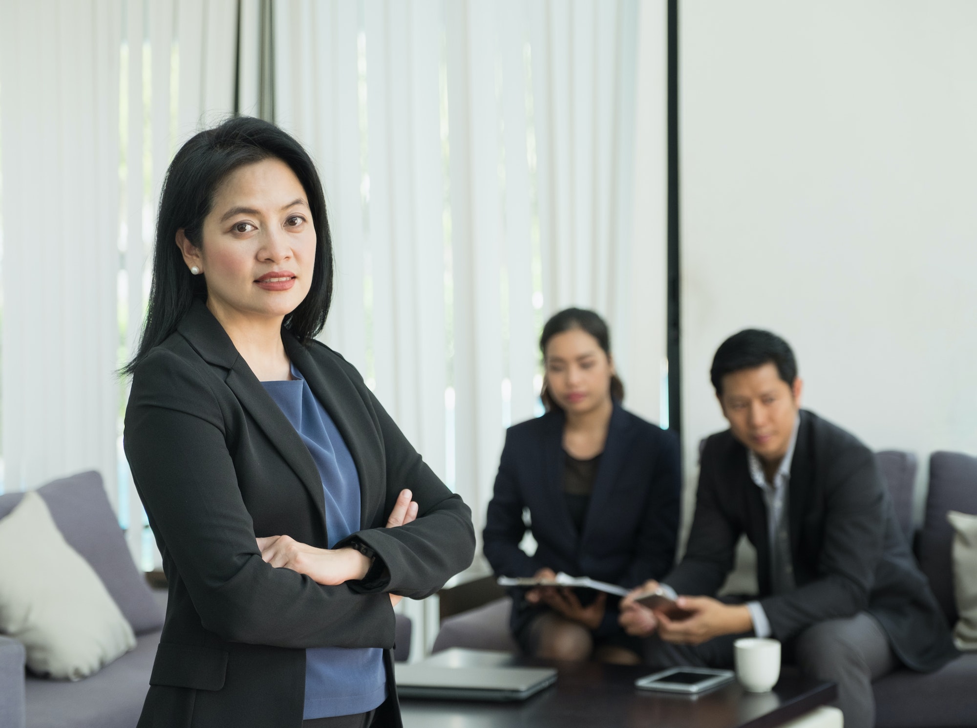 Businesswoman female leader standing and cross arm with team in corporate meeting